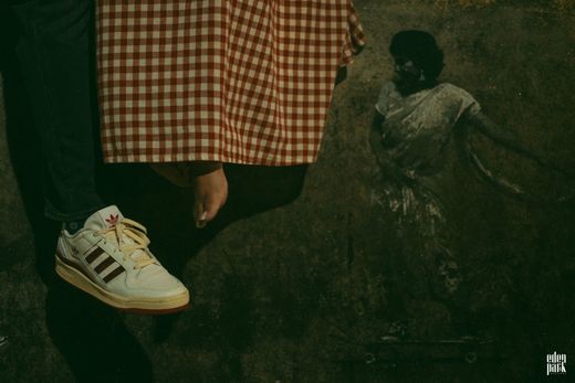 Steeja's white trainers on the ledge, below the hem of her red checked dress.