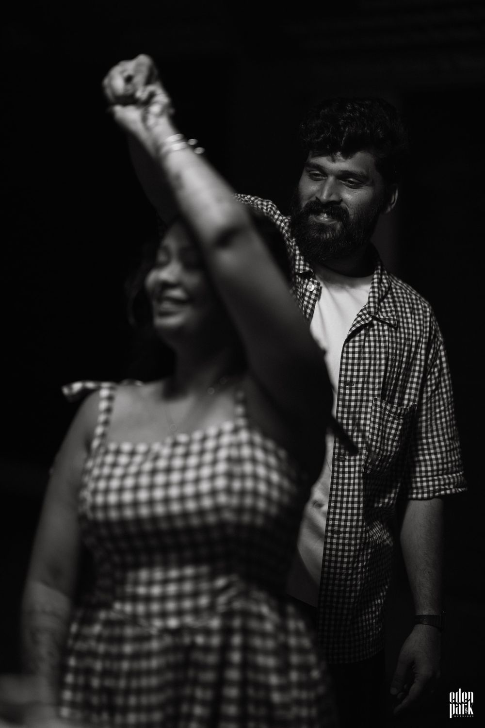 Black and white: Arjun throws a fist into the air mid-laugh while Steeja grins beside him.